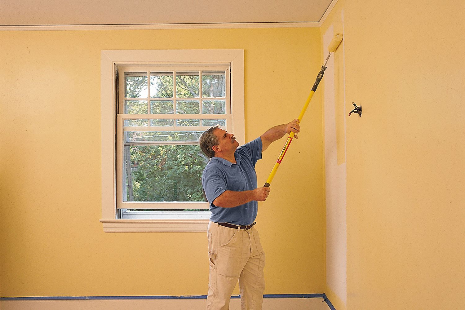 a man painting a large wall in a room
