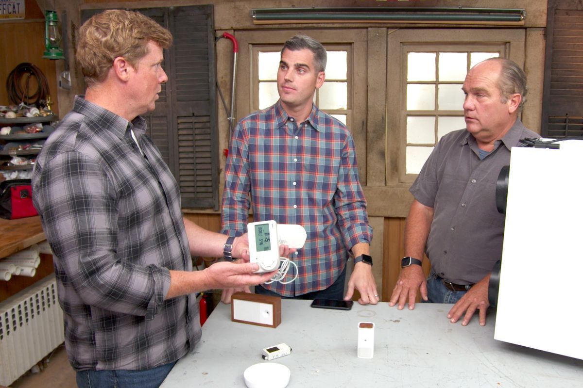 3 Men looking at an indoor air quality monitor.