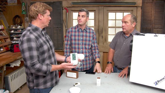 3 Men looking at an indoor air quality monitor.