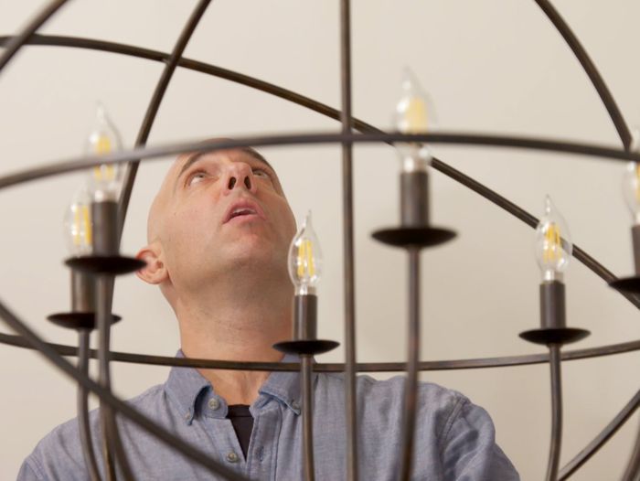 A man using a light lift to work with a high hanging fixture.