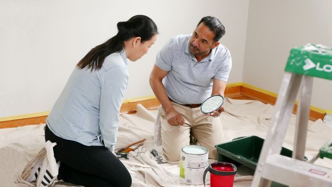 Two people on a paint tarp preparing to paint a nursery.