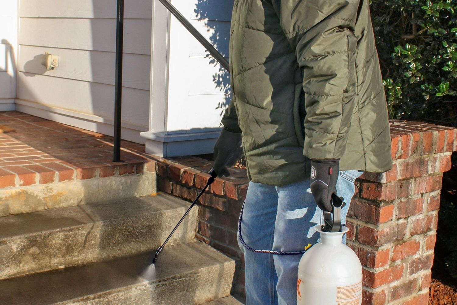 Photo of a man spraying a pet-safe ice prevention method on outdoor stairs