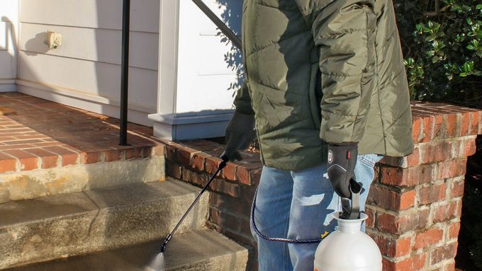 Photo of a man spraying a pet-safe ice prevention method on outdoor stairs