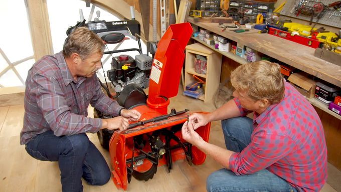 Two experts working on maintaining a snowblower.