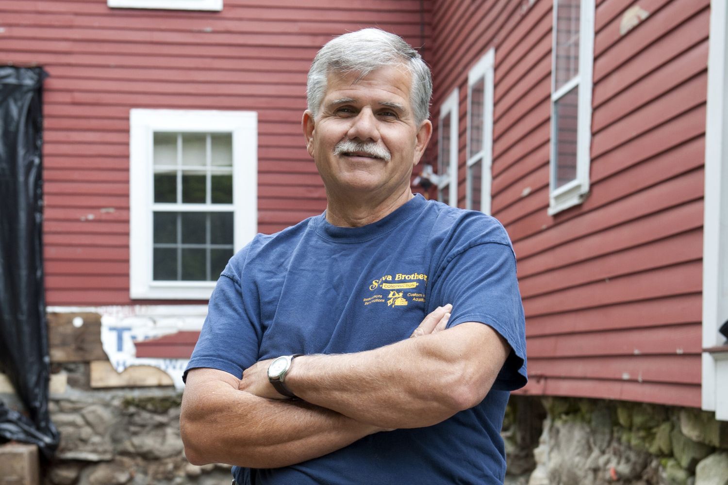 An image of Tom Silva standing in front of a red home.
