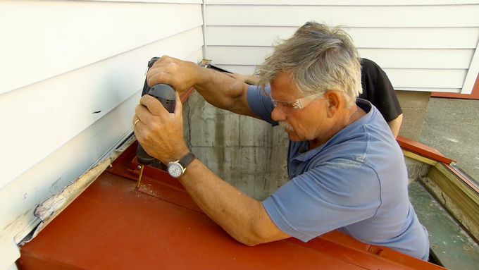 A man using a drill to install bulkhead doors.