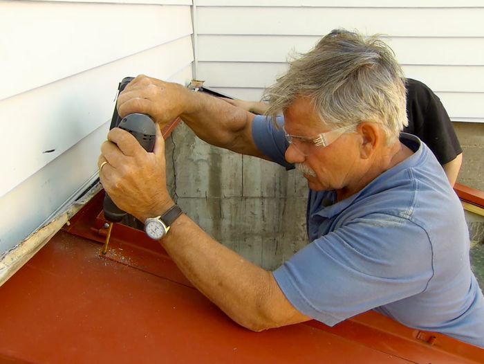 A man using a drill to install bulkhead doors.