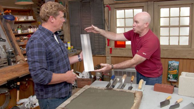 Two men talking while the one on the left holds a masonry trowel.