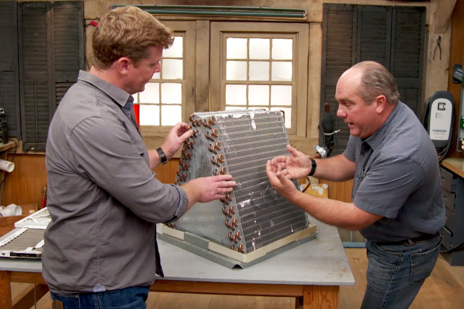 Photo of two people looking at an air conditioning system that uses Freon, which is now a banned chemical.