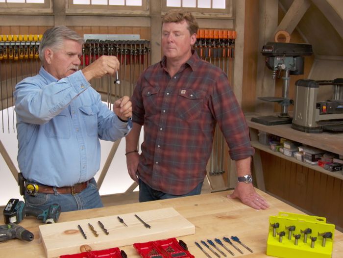 Two men looking at drill bits.