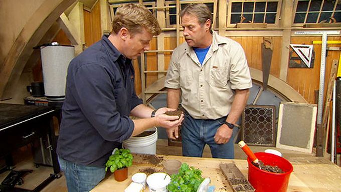 Two men preparing to plant seeds in soil.