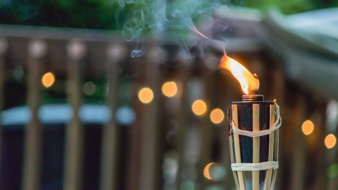 a tiki torch in a backyard that is lit