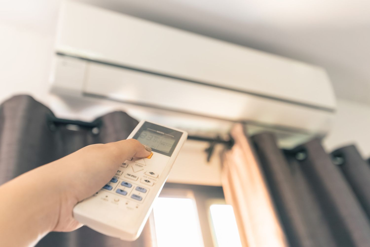 Person using a remote to turn on an air conditioning unit
