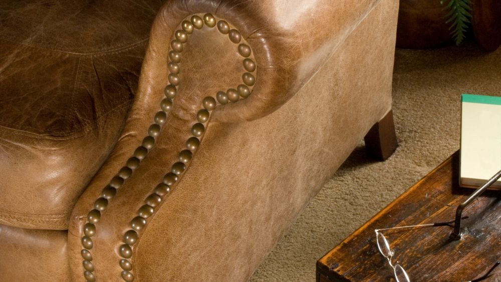 Worn brown leather chair in need of repair.