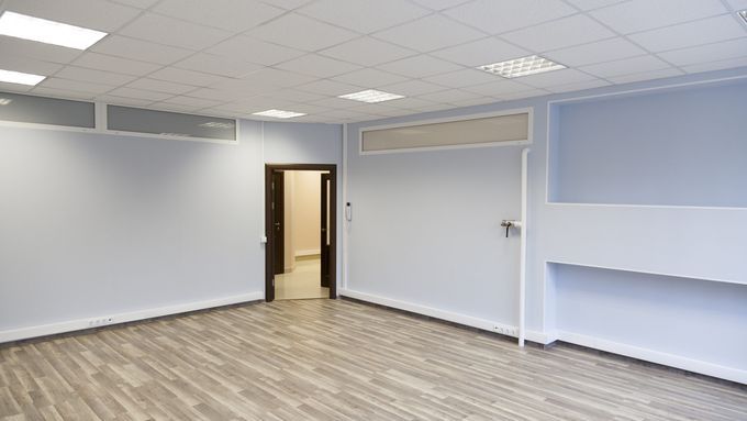 An empty room with an open door in the corner and a drop ceiling.