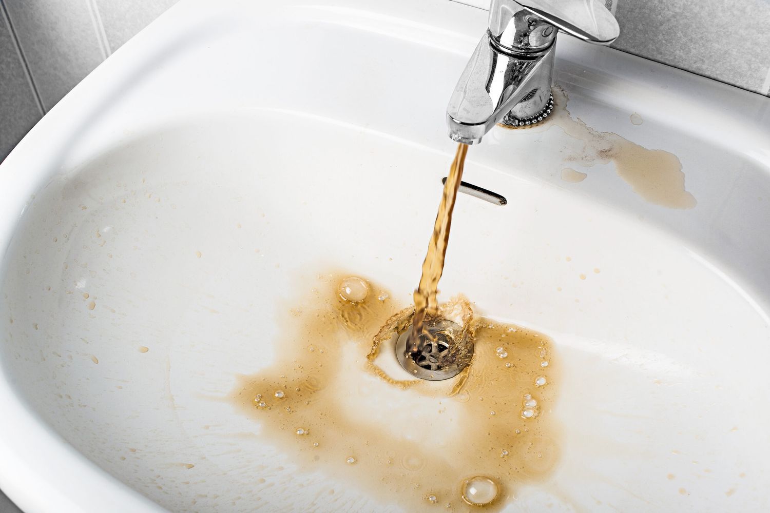 Well water with iron and rust in it pouring from a faucet.