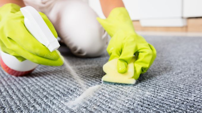 A person using a spray bottle to remove carpet stains.