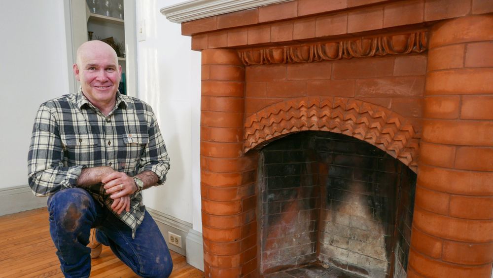 Image of a person standing next to a brick fireplace