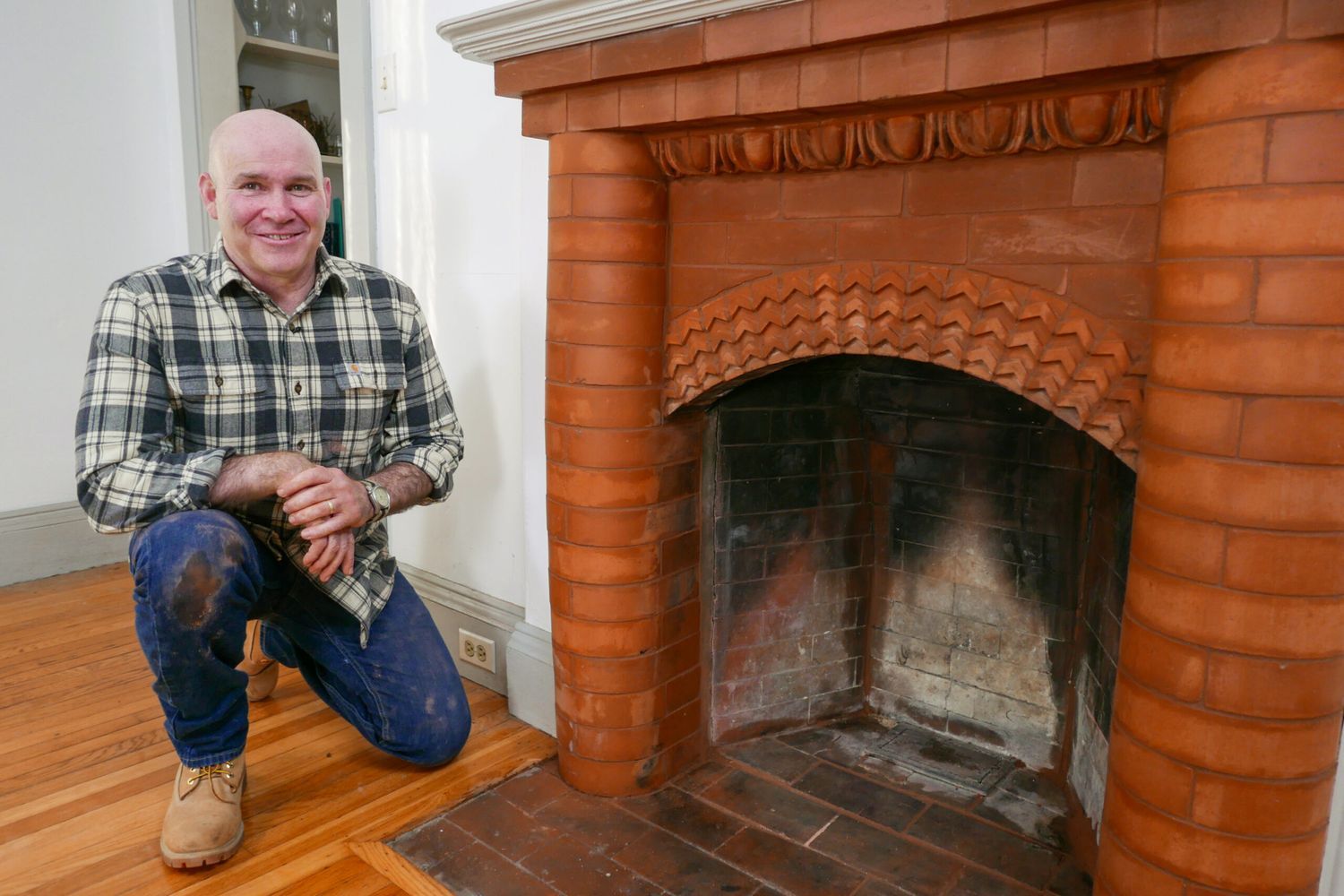 Image of a person standing next to a brick fireplace