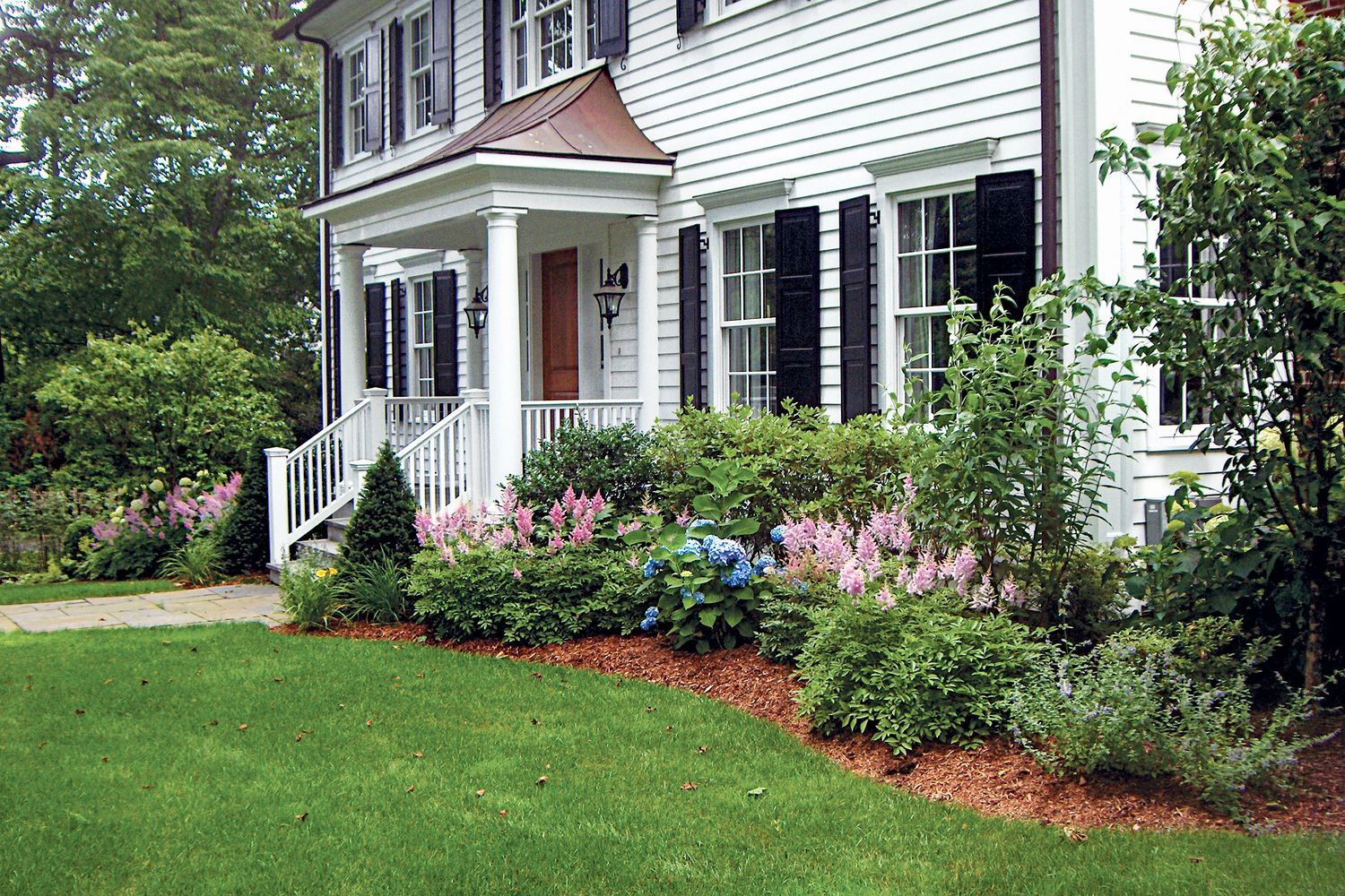 A home with various plants included in it foundation planting.