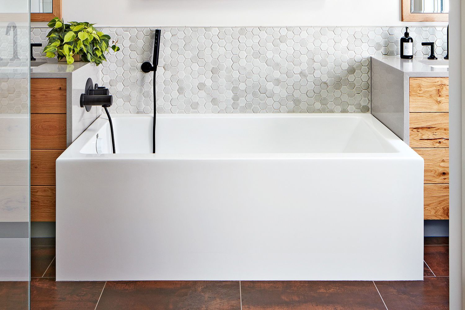 A bathtub with a mat in a small bathroom.
