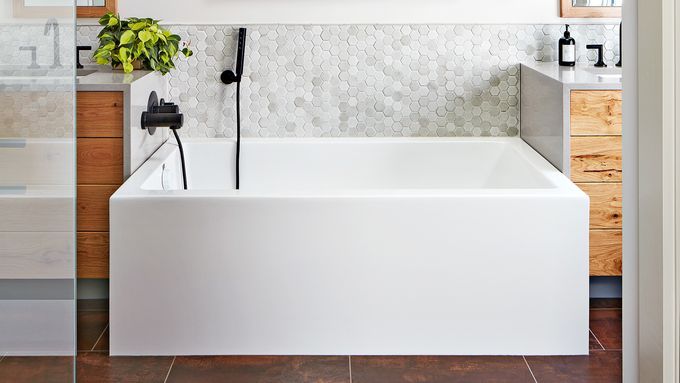 A bathtub with a mat in a small bathroom.