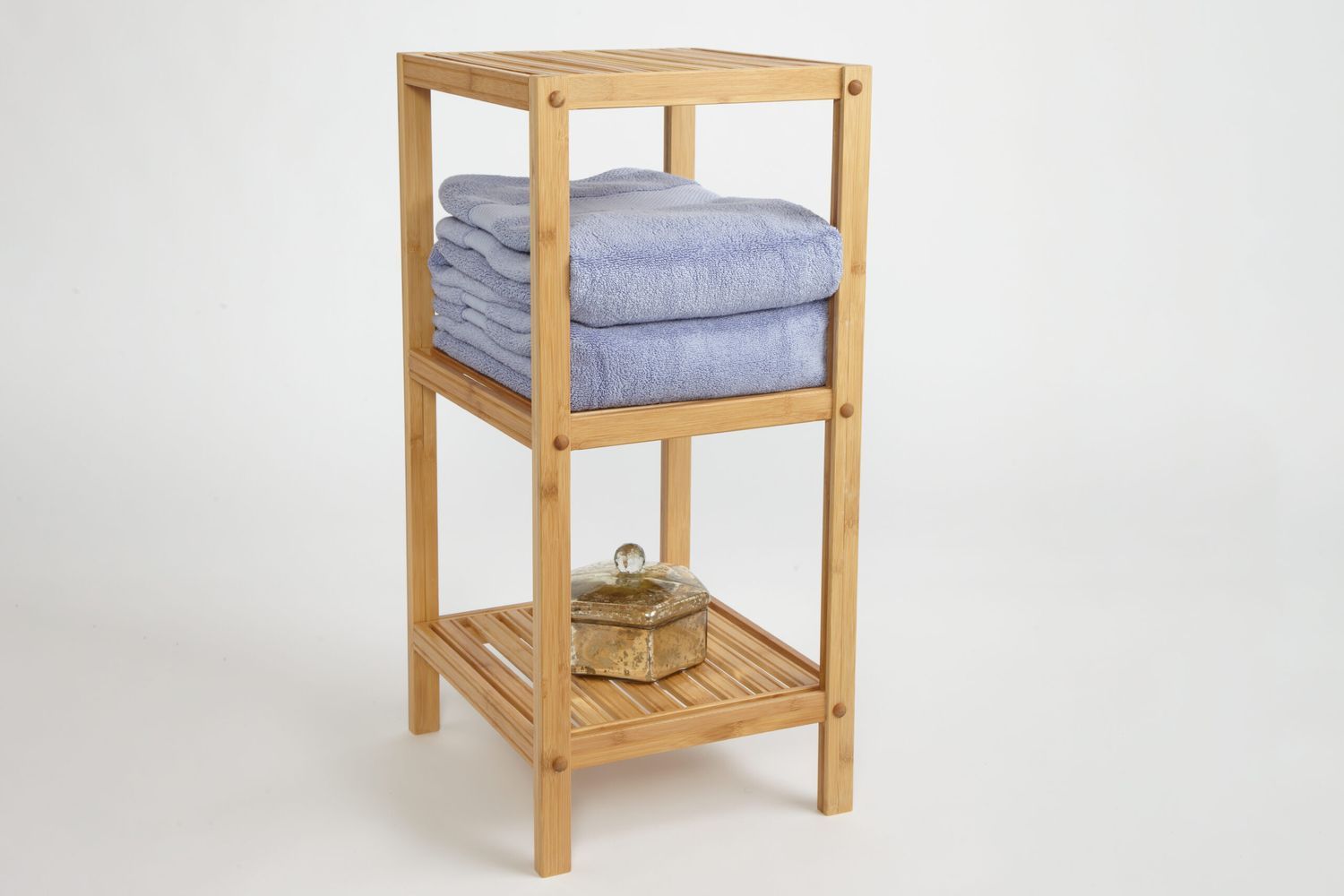 A three-tiered bath stand with blue towels on it.