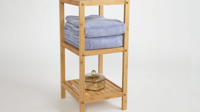 A three-tiered bath stand with blue towels on it.