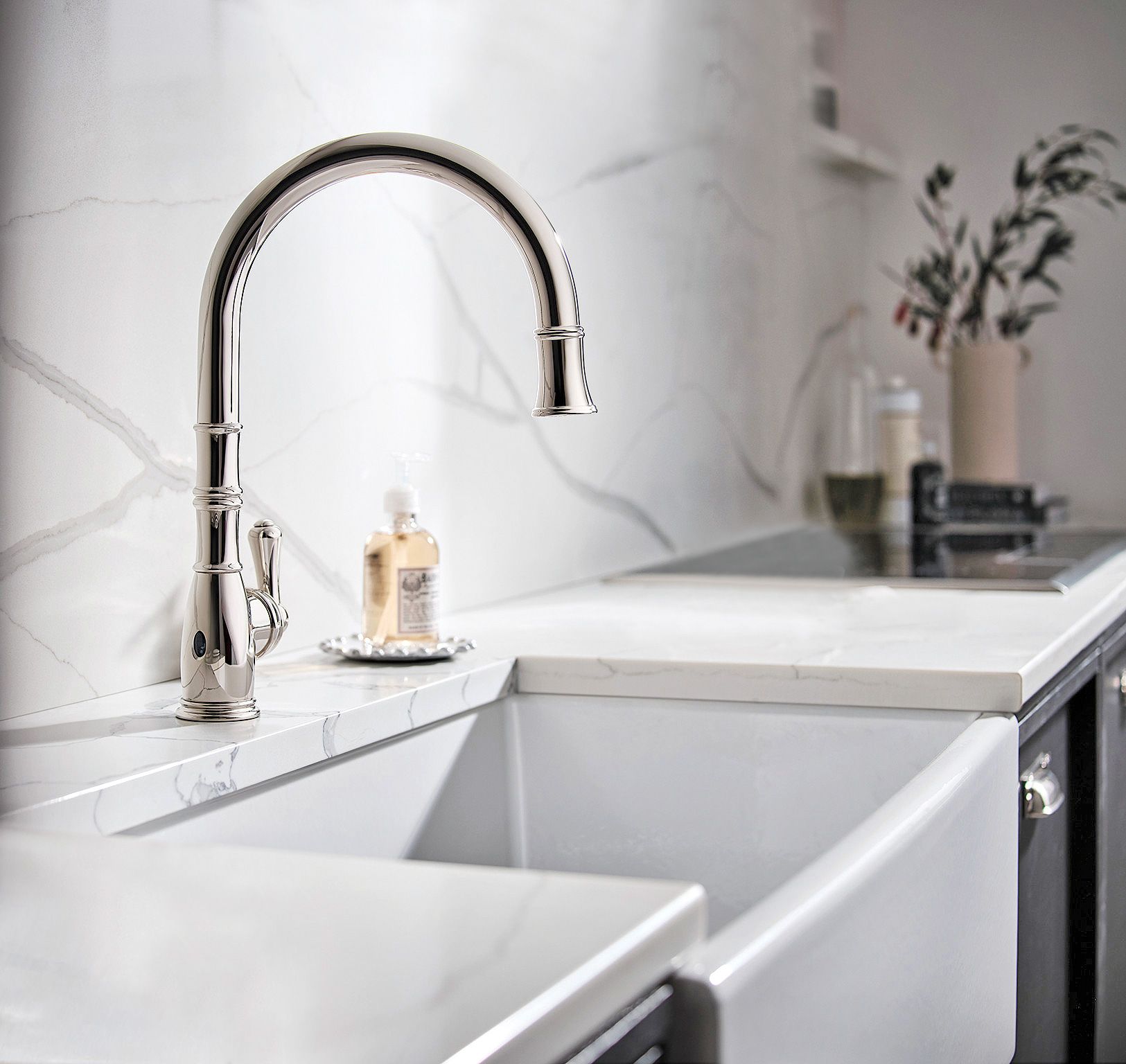 Gray kitchen pantry cabinets accented with brushed brass hardware flanks  gray raised p…