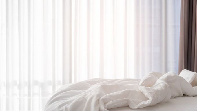 A bedroom with gentle light coming through to aid with sleep.