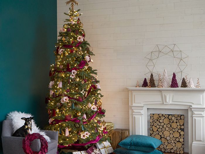 A Christmas tree in front of a fireplace.