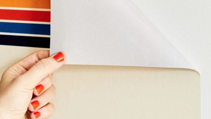 A person applying peel and stick striped wallpaper to a wall.