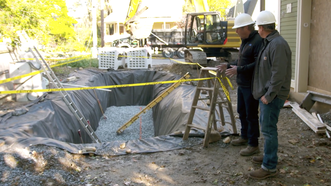 A dry well being installed next to a home.