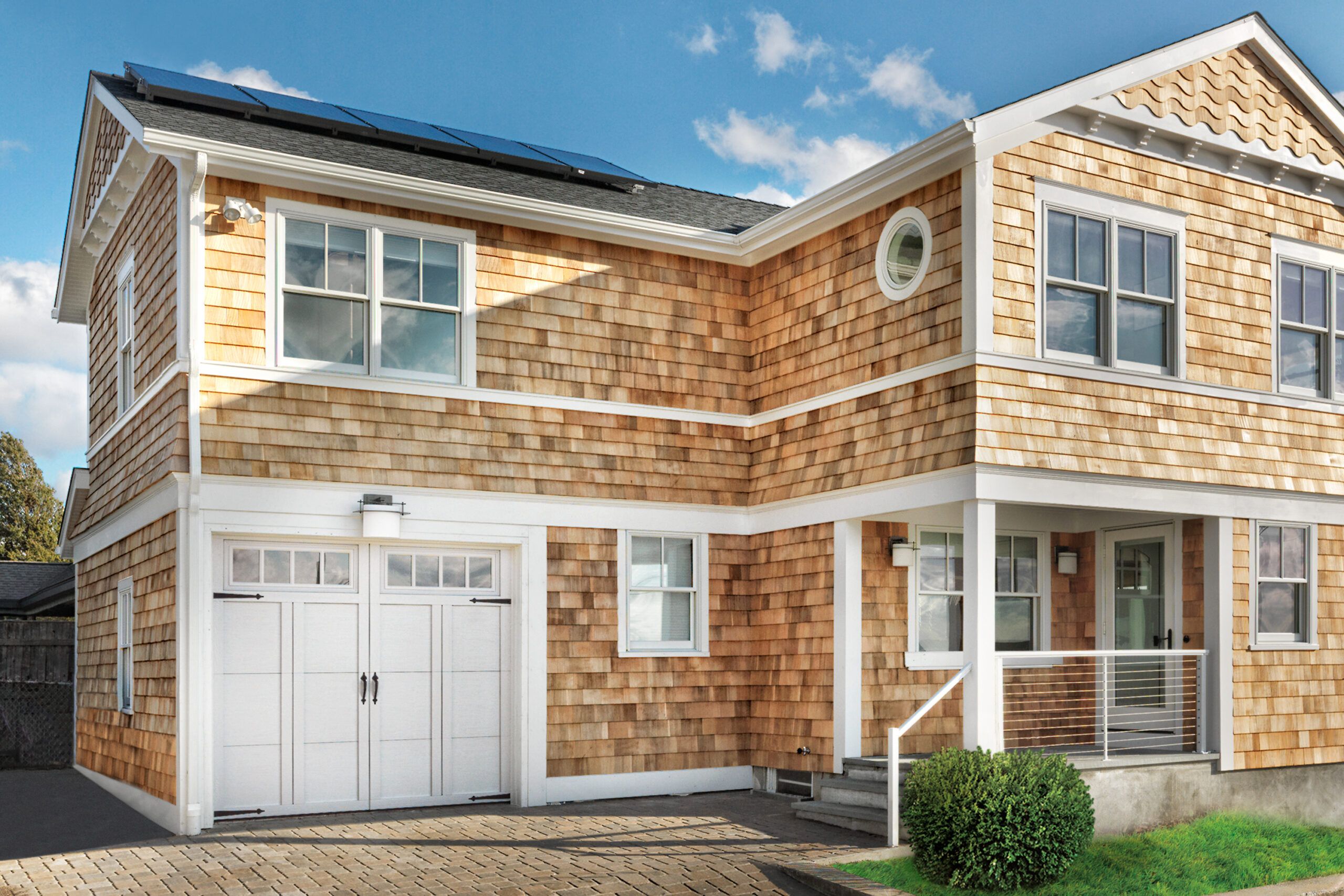 A 2 story home with yellow siding and an addition above the garage.