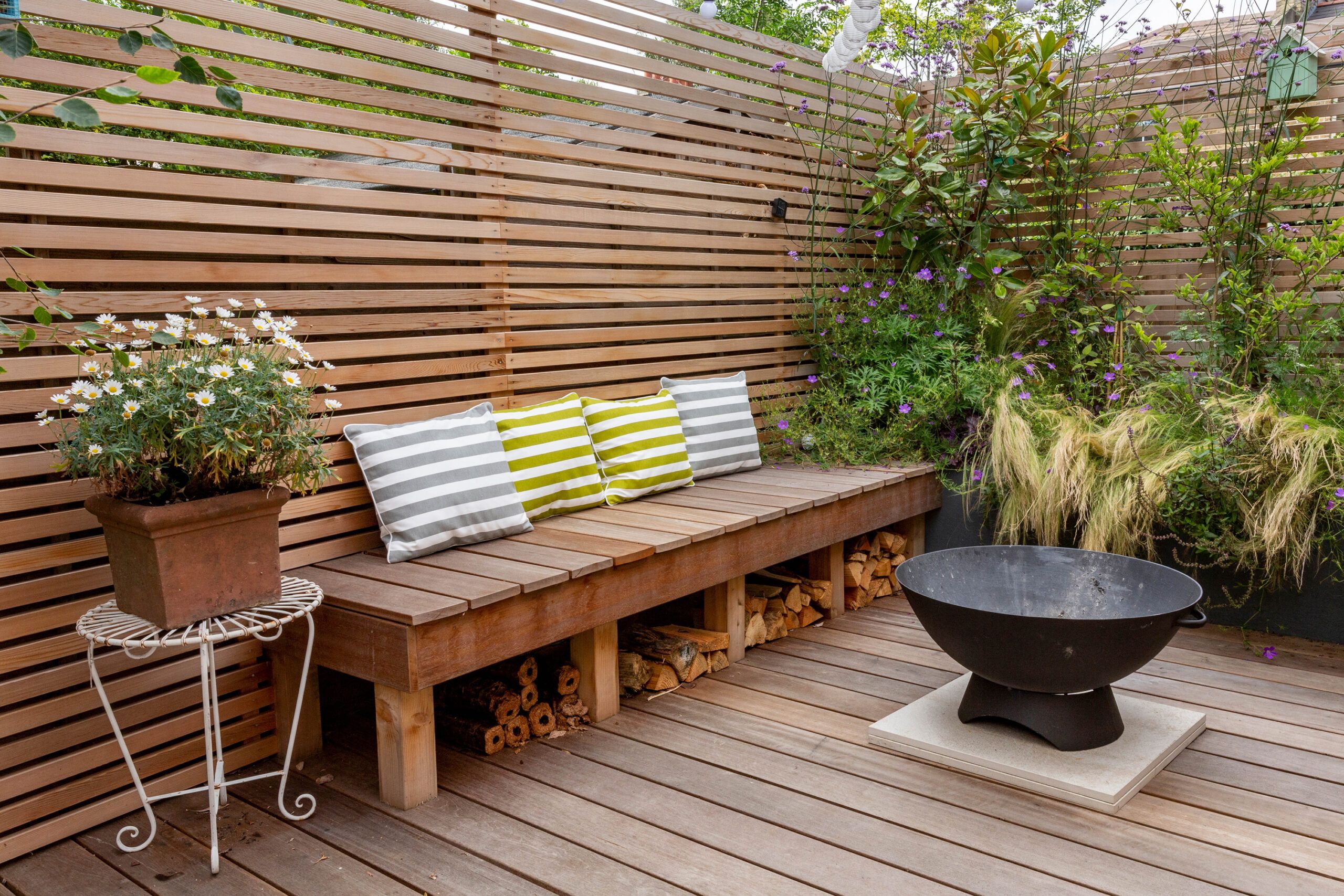 A louver fence with plants beside it.