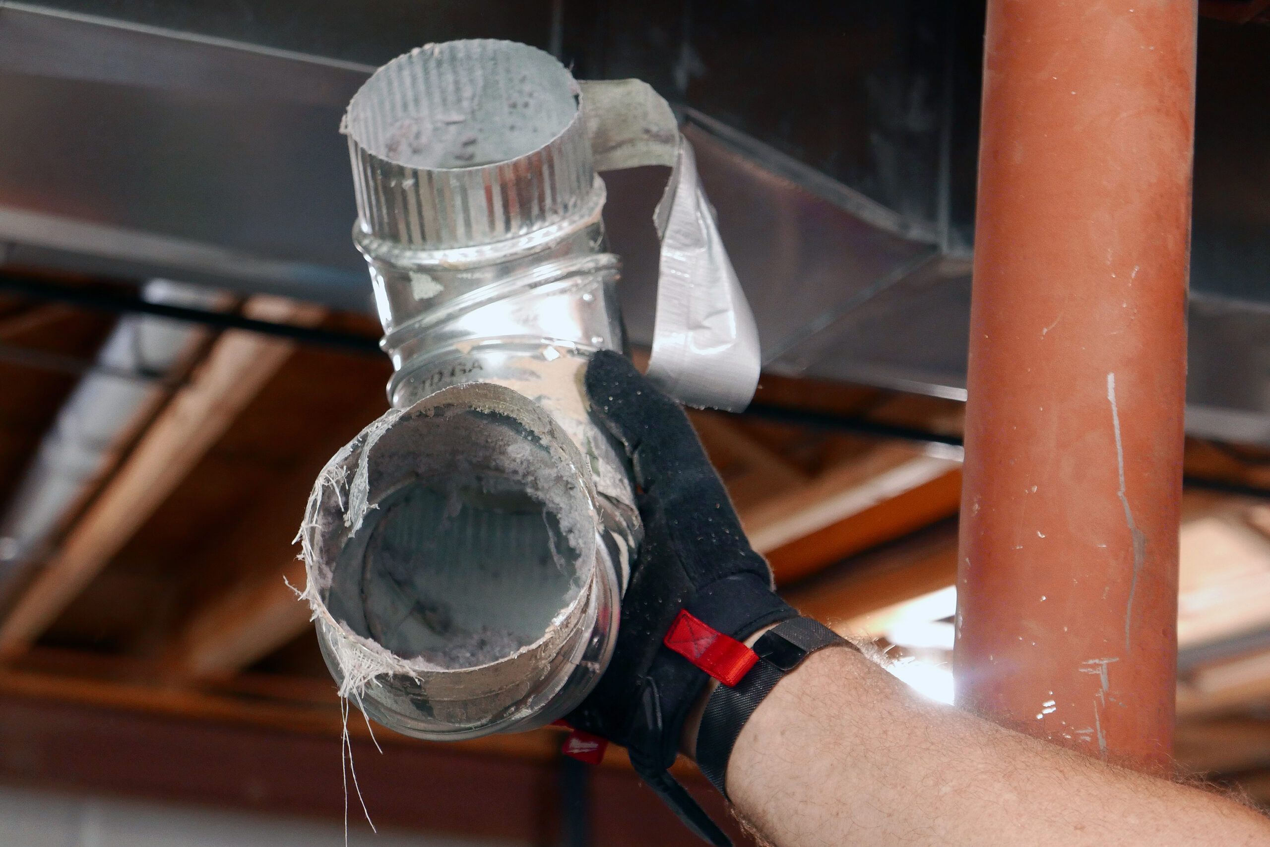 A metal  duct with dust and lint in it from a dryer vent that needs to be cleaned.