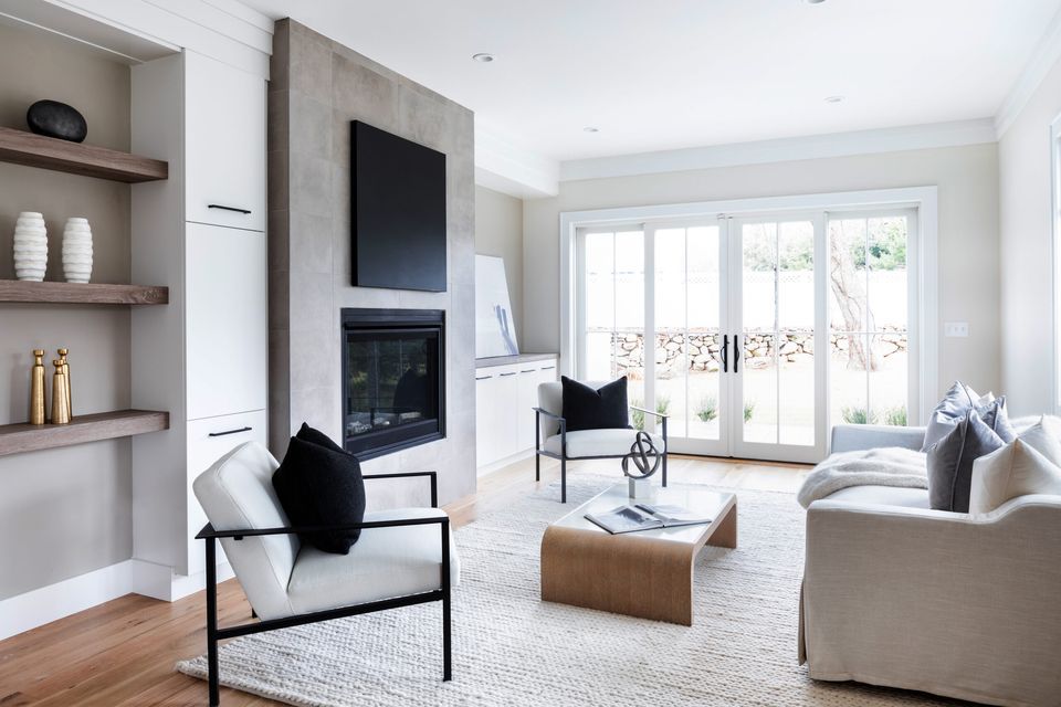 A clean home with a grey couch and table. A large window sits in the background.