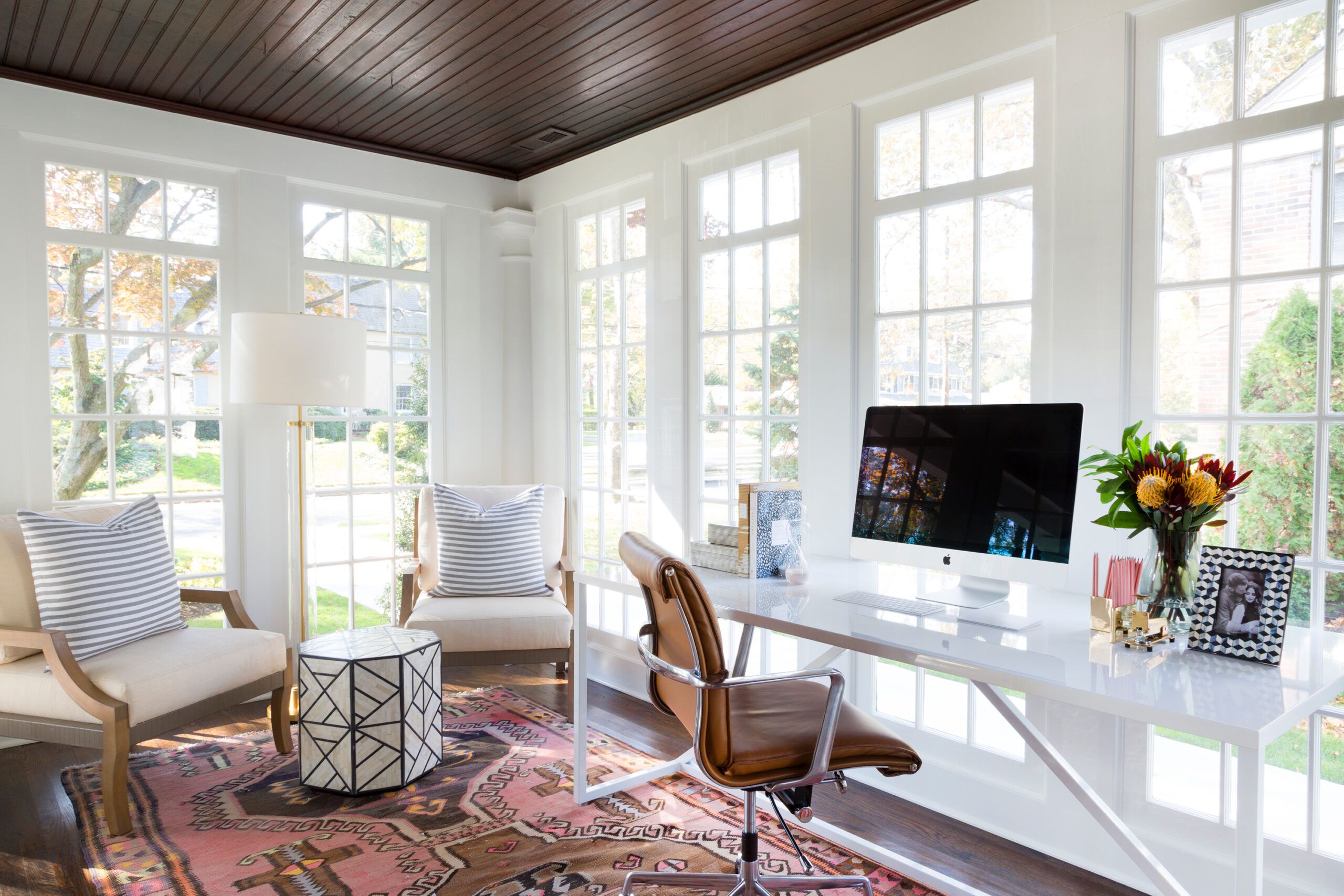 Image of a home office sunroom, with a desk and office chair along with some additional seating