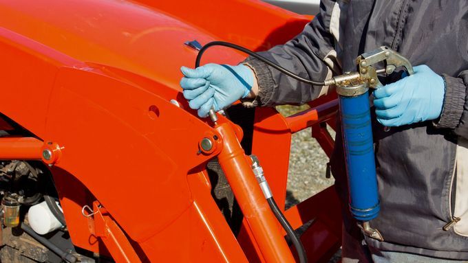 A man using a grease gun for a car repair.