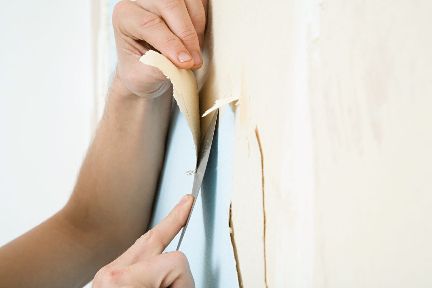 Someone removes wallpaper and wallpaper boarders from the wall.