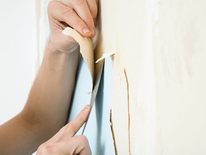 Someone removes wallpaper and wallpaper boarders from the wall.
