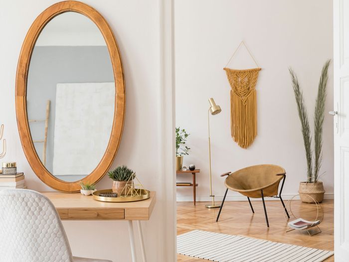 Glass mirror cut into an oval shape and set in a wooden frame.