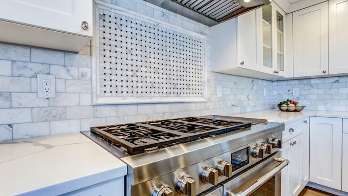 Lifestyle image of a stainless-steel cooking range in a sparkling modern kitchen. Cover image for the This Old House Reviews Team's guide on how to remove scratches from stainless steel surfaces.