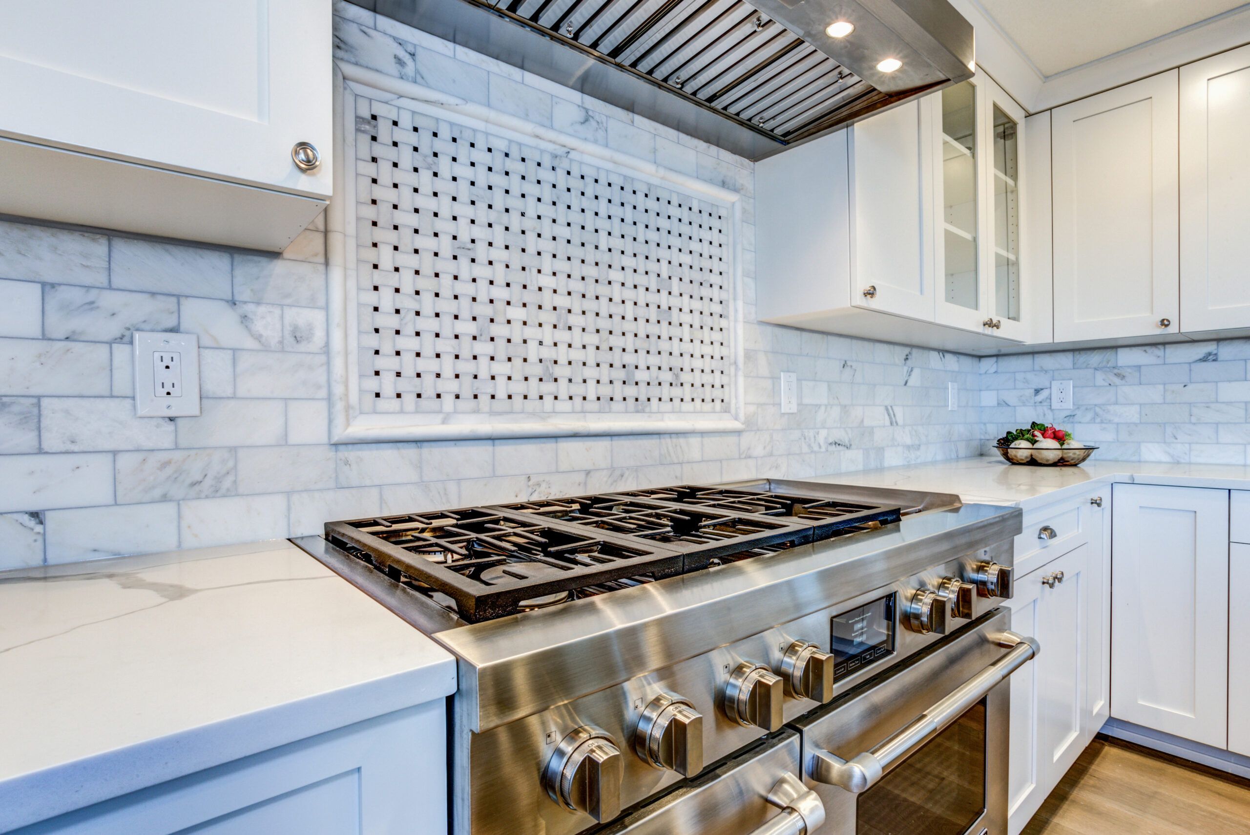Lifestyle image of a stainless-steel cooking range in a sparkling modern kitchen. Cover image for the This Old House Reviews Team's guide on how to remove scratches from stainless steel surfaces.