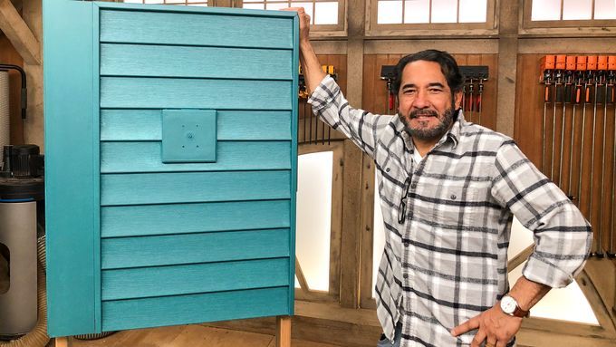 A man standing behind a piece of painted vinyl siding.