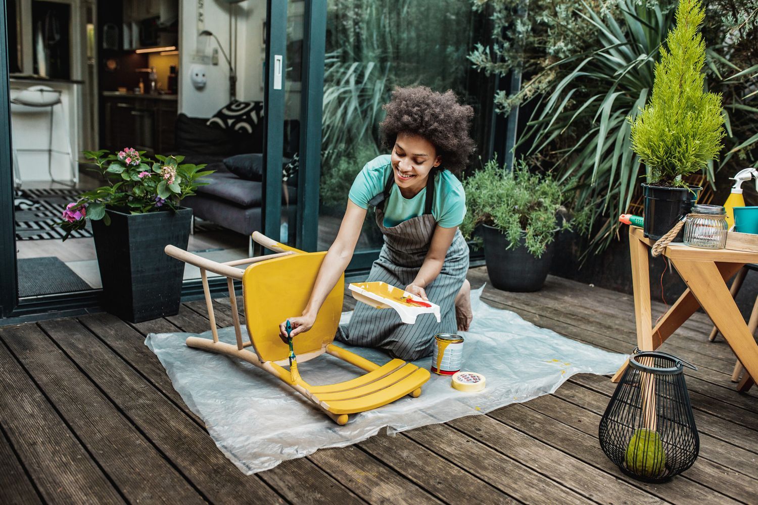 Woman painting a wooden chair yellow.