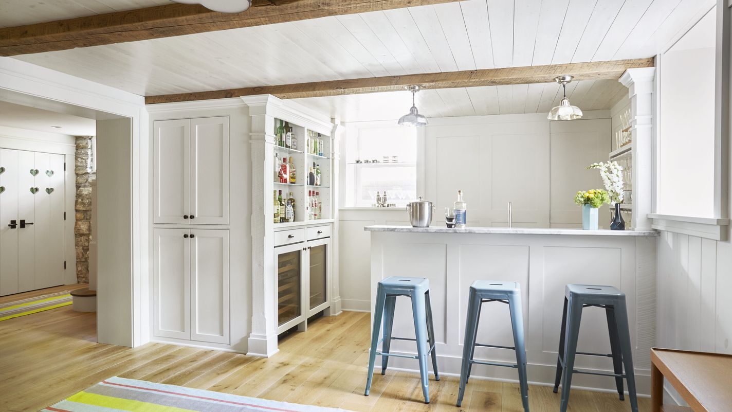 A basement kitchen with a breakfast bar and a painted wood plank ceiling.