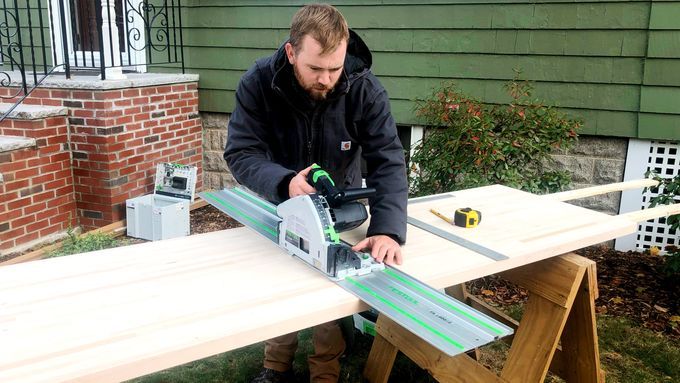 A man constructing butcher block countertop with a cutting tool.