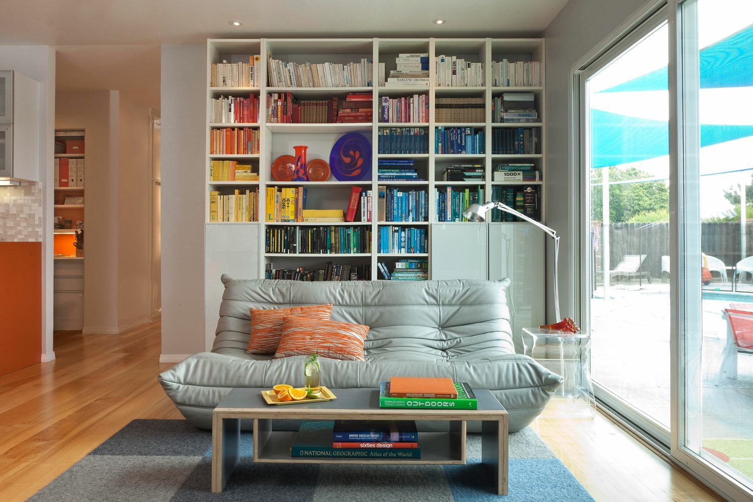 A sitting room with a home library and windows.