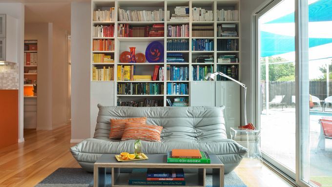 A sitting room with a home library and windows.